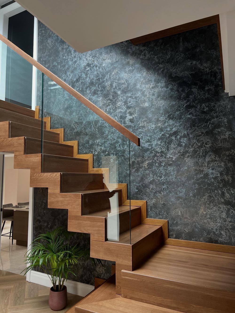 Marbled plaster wall in deep teal behind a floating oak staircase